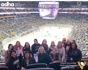 Group of RDHs standing in skybox suite at PPG Paints Arena during a Penguins hockey game.