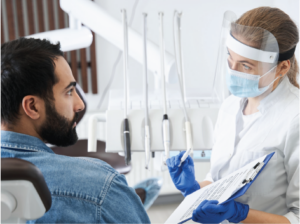 Male patient in dental operatory with dental hygienist filling out medical forms