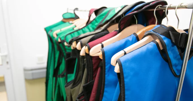 Patient shielding vests in various colors on hangers.