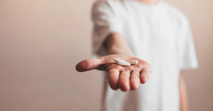 Child in white t-shirt hold hand out with pills in hand