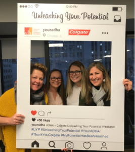 Carmen and colleagues peering through a picture frame at ADHA corporate in Chicago.