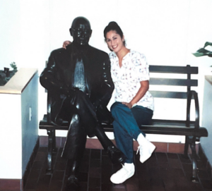 Carmen seated on a bench at Tufts University Dental Medicine School next to a statue.