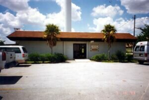 Small white building with orange roof and broad parking lot