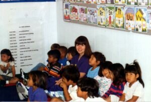 Becky in blue scrubs seated with Miccosukee children.