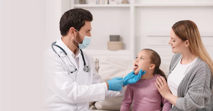 Primary care physician looking in mouth of young patient