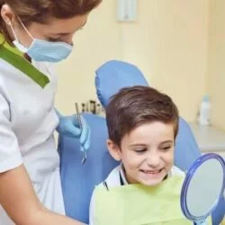 Child in dental chair looking at handheld mirror