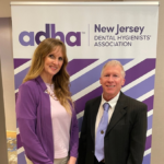 Two representatives from the NJDHA standing in front of a pull up banner from the constituent