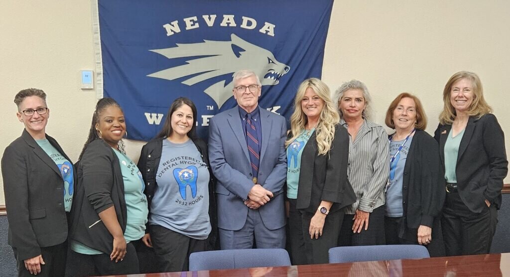 A group of 7 NV hygienists pose with Nevada State Senator Skip Daly in a conference room.