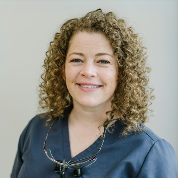 Headshot of Jessica Atkinson in blue scrubs with loupes around her neck.