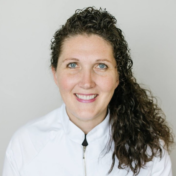 Headshot of Shelley Brown in white jacket with long brown hair tied back
