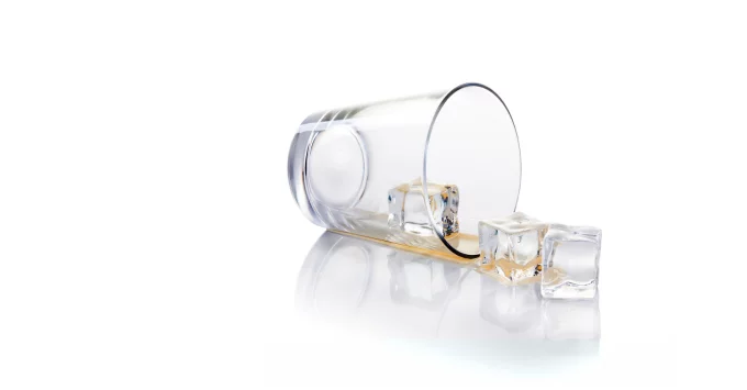 Empty glass on its side with ice cubes rolling out.