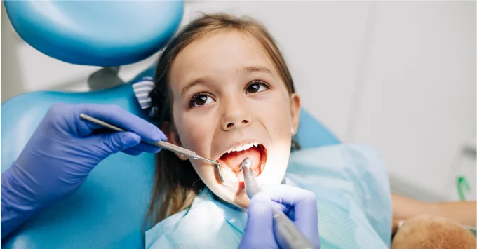 Young girl in dental chair with mouth open during exam