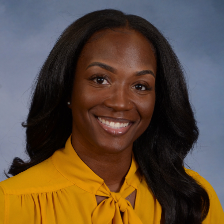 Headshot of Jazmyn Ragland with long black hair down in yellow blouse