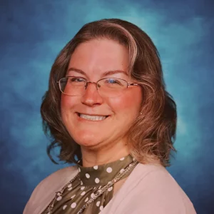 Christina Emmert RDH, PHDH, PRP, FADHA headshot photo pink sweater, polka dot blouse.