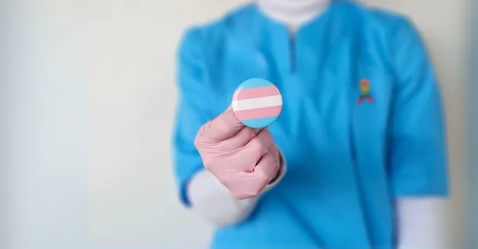 Dental Hygienist in scrubs holding transgender pin