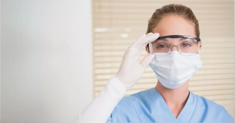 Hygienist in goggles and mask looking at camera