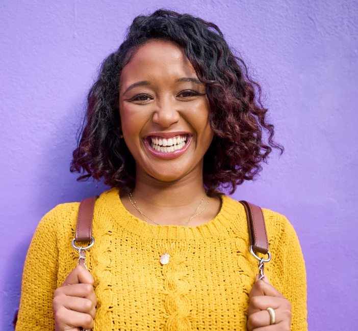 young woman in yellow sweater against purple wall
