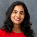 Anitha Peddireddy BDS, MDS, PhD smiling in red dress.