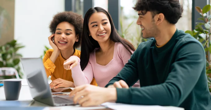 Students smiling around a laptop