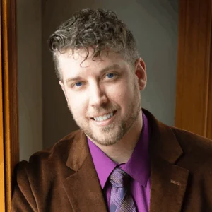 Ryan Rutar in brown jacket with purple shirt and tie, smiling