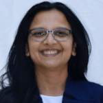 Sonika Masih, Ed.D., BDS, RDH smiling in blue jacket and white top with glasses.