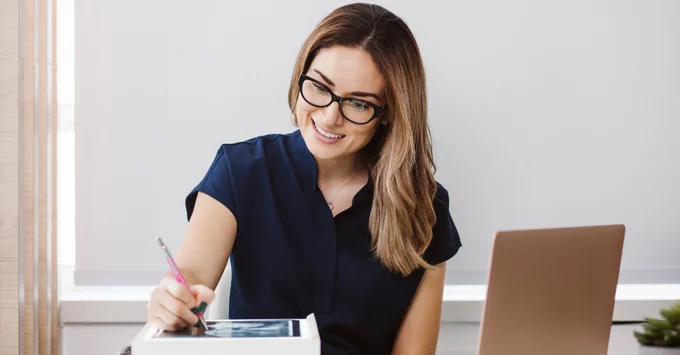 Hygienist with glasses at laptop with digital pen