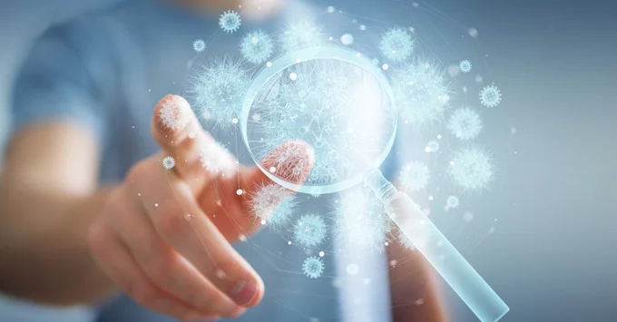 Hand on computer screen with magnifying glass