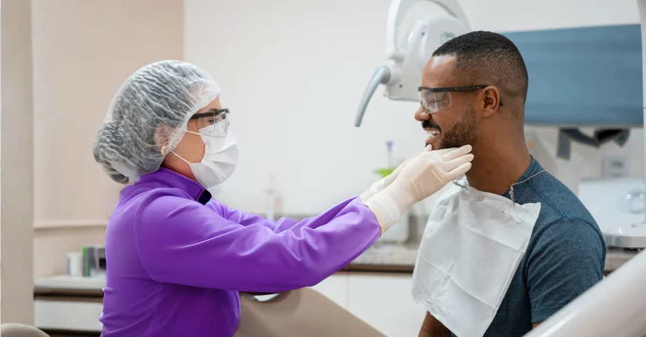 Hygienist palpating mandible of patient in operatory