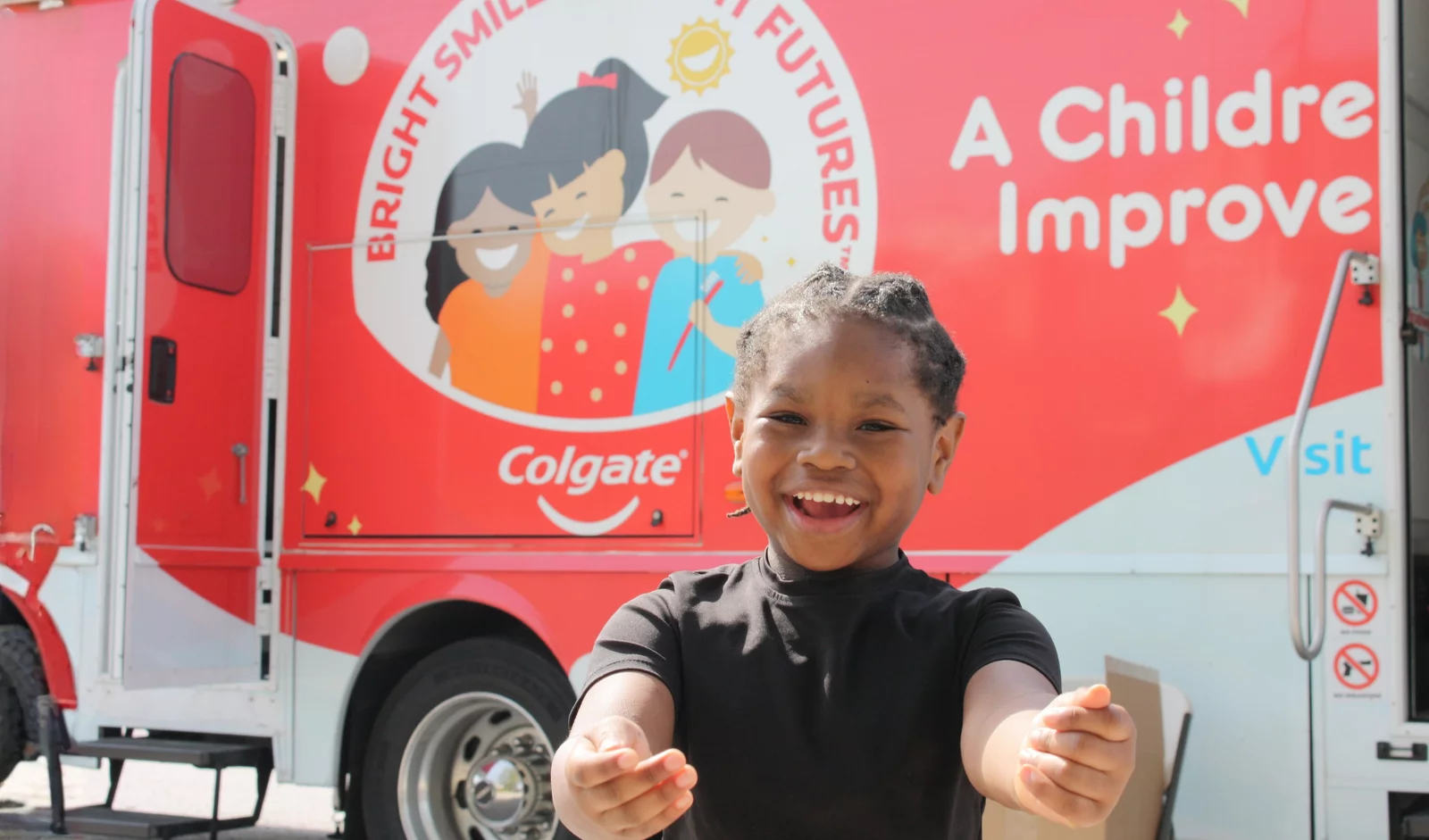 Young child with arms outstretched in front of BSBF mobile dental van