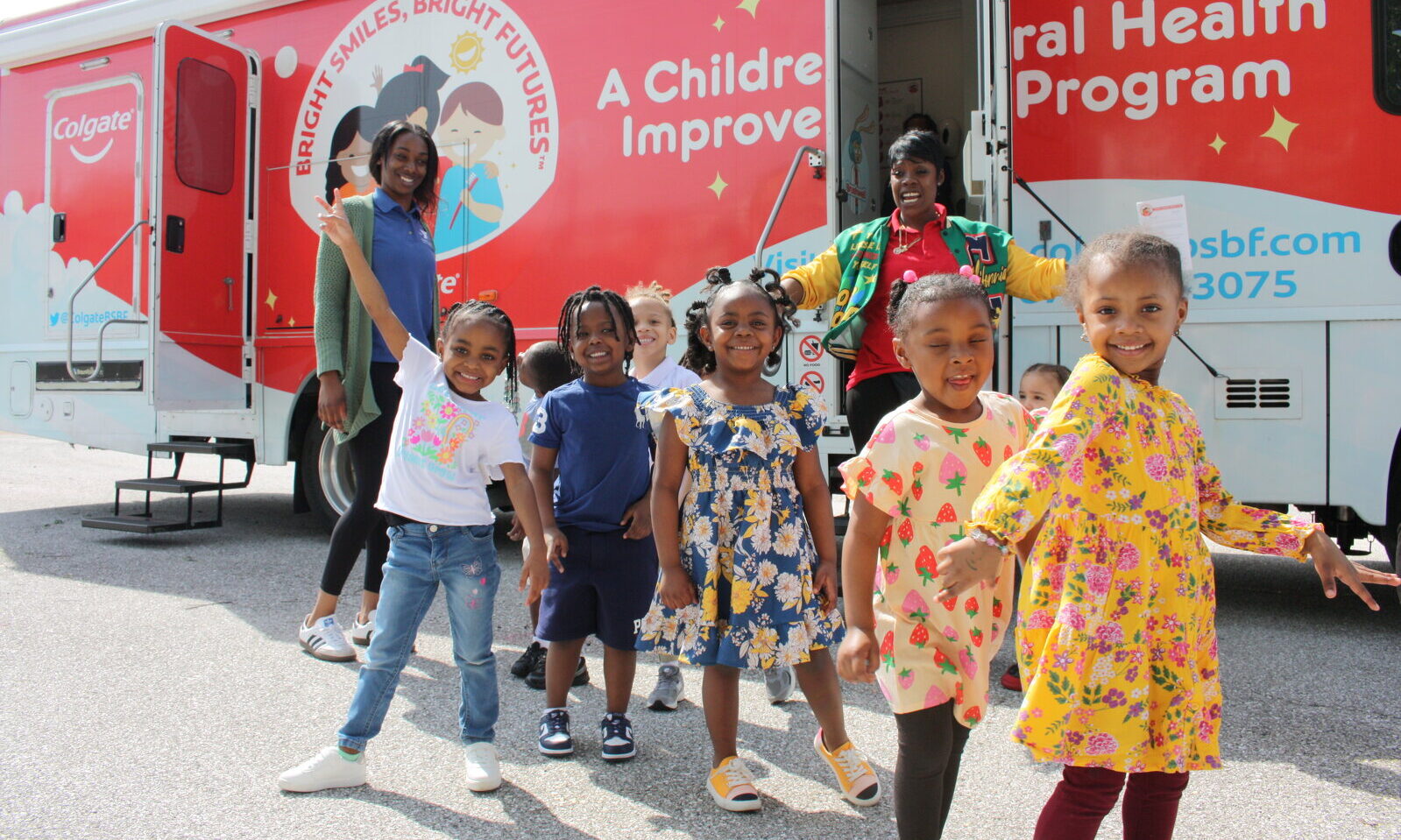 Youngsters smiling and posing in front of a BSBF Mobile Dental Van