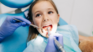 Girl in operatory char opening mouth.