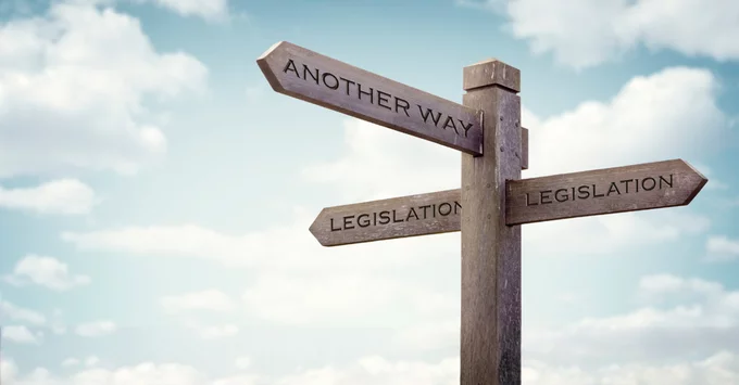 Wooden cross roads sign with Another Way and Legislation words