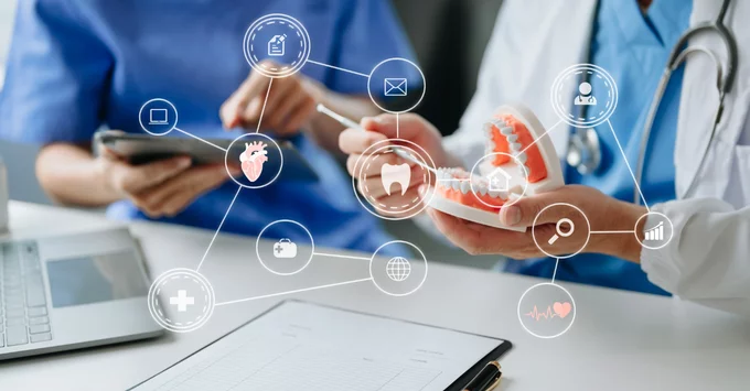 Hand with tablet and hand holding tooth model in medical setting