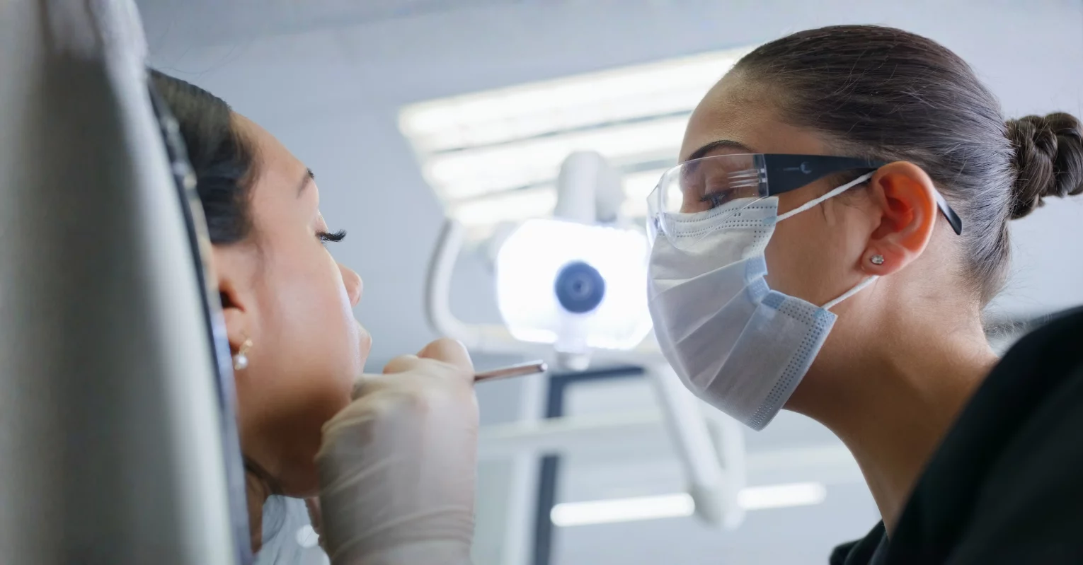Dental Hygienist in mask and goggles working with a patient in the operatory