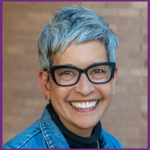 Elizabeth Ramos headshot in blue jacket with black large frame glasses