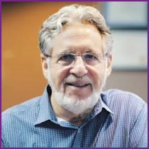 Howard Hindin DDS headshot in blue button down shirt, smiling with glasses and beard