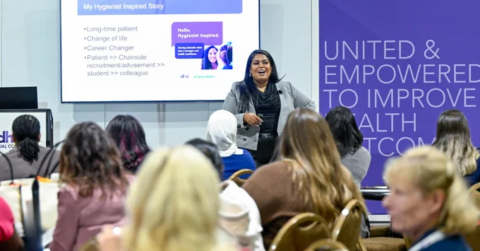 Marlyce James standing at the front of a room facing a seated crowd and presenting